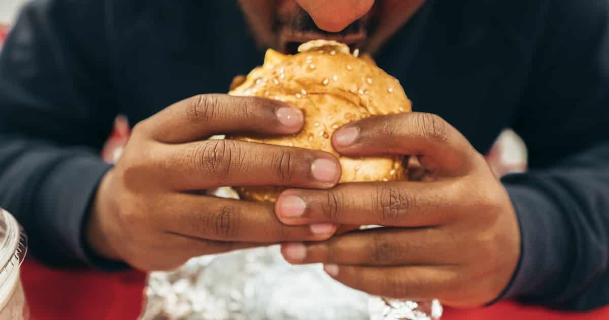 A man holds a burger to his mouth