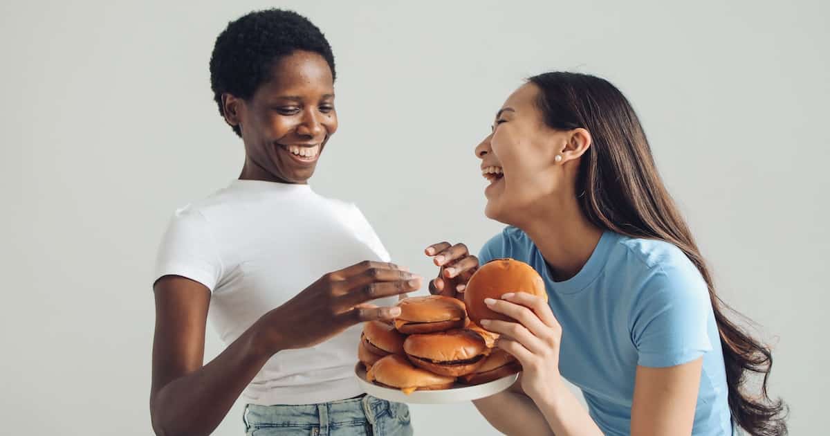 two women laughing with a plate of hamburgers