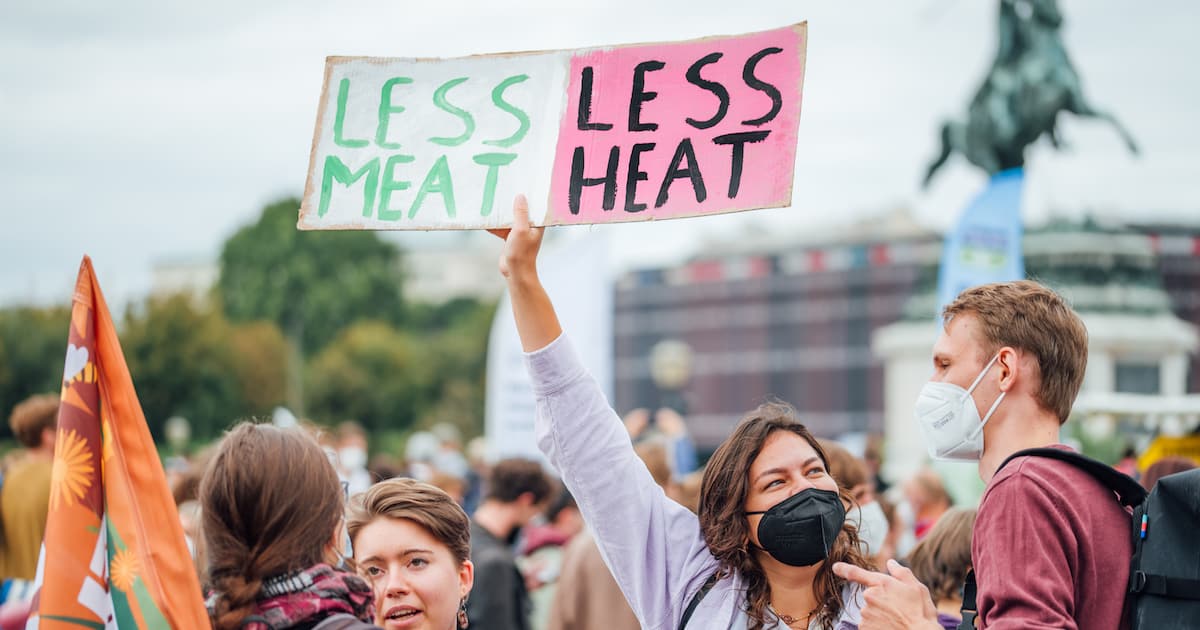 Protester holding a banner with a message 'Less meat, less heat'