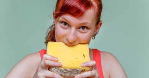 Girl biting into a block of cheese