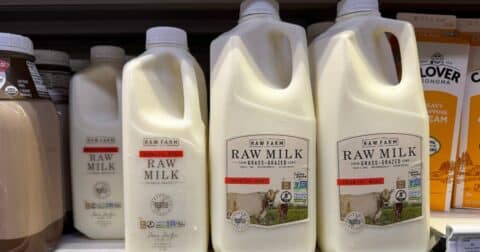 Containers of Raw Farm raw milk are displayed on a shelf.