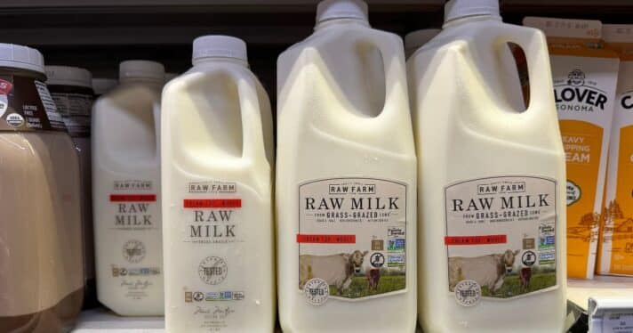 Containers of Raw Farm raw milk are displayed on a shelf.