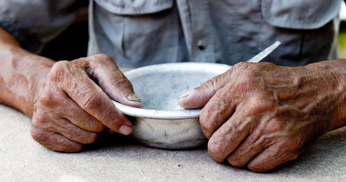 a pair of older-appearing hands grasps a bowl, seated at a table, Blue Zones docuseries debuts on Netflx