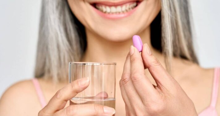 woman posing with supplement and water glass, collagen explainer