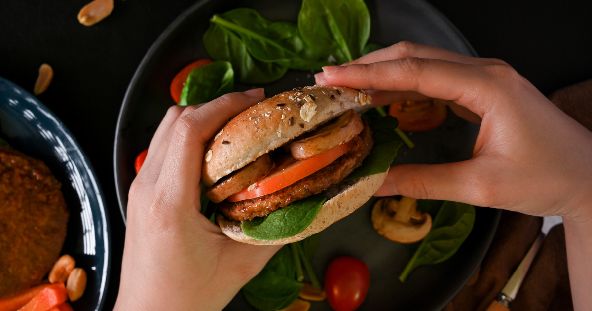 Closeup of a plant-based burger in two hands.