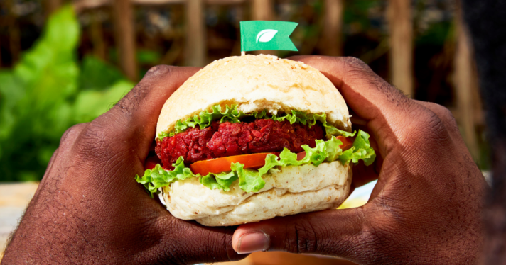 Closeup of two hands holding a plant-based burger