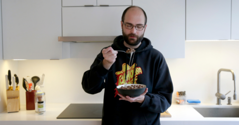 A man eating a bowl filled with meat and cheese