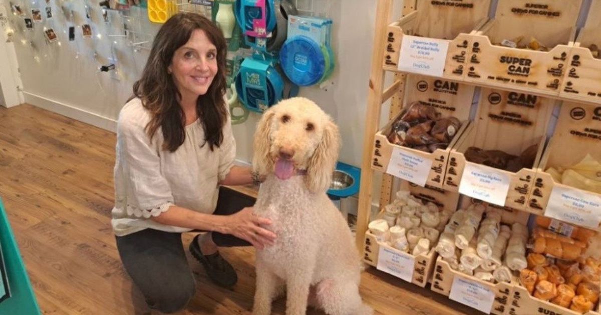 Lisa Castagnozzi kneels on the floor with a white dog.