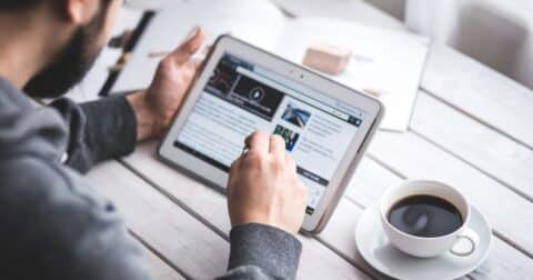 A man holds a tablet opened to a news site