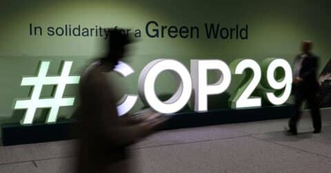 Attendees walk past the COP29 logo during the United Nations Climate Change Conference