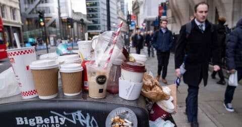 Coffee and soft drinks cups from some of the major take away food and drinks companies piled up on top of an overflowing street trash can