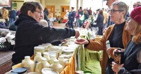 Person waits on customers at a cheese booth at a farmer's market