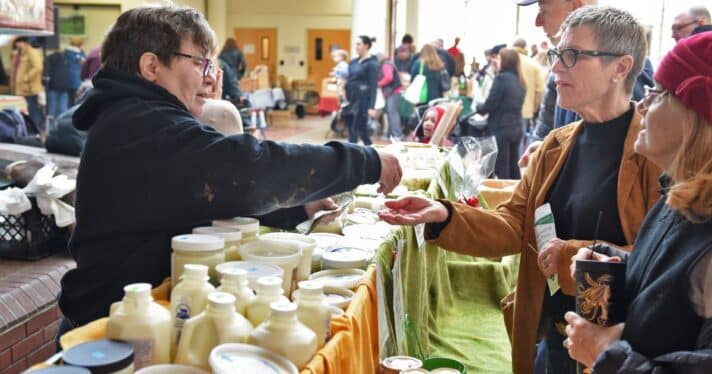 Person waits on customers at a cheese booth at a farmer's market