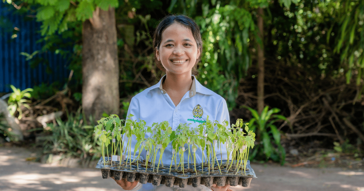 A young person holding a container of plants