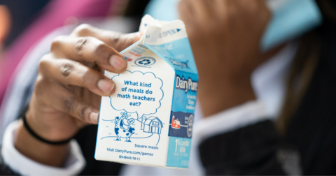 A young student holding a milk carton