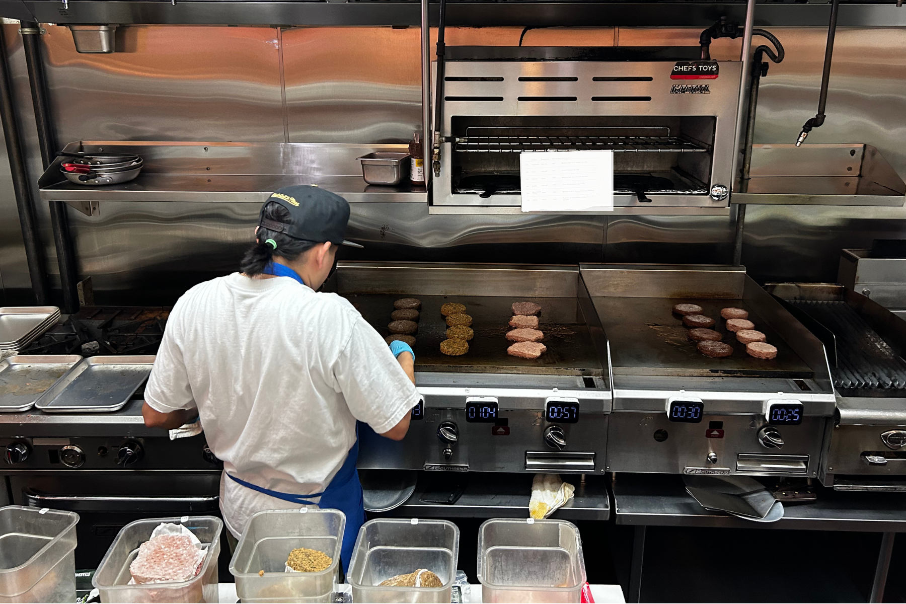 A line cook on the grill cooking burgers