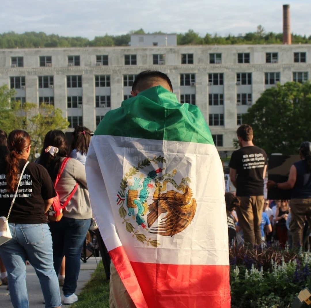 A protester stands with the Mexican flag wrapped around his body.