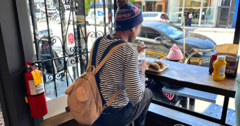 A patron eating food by a window
