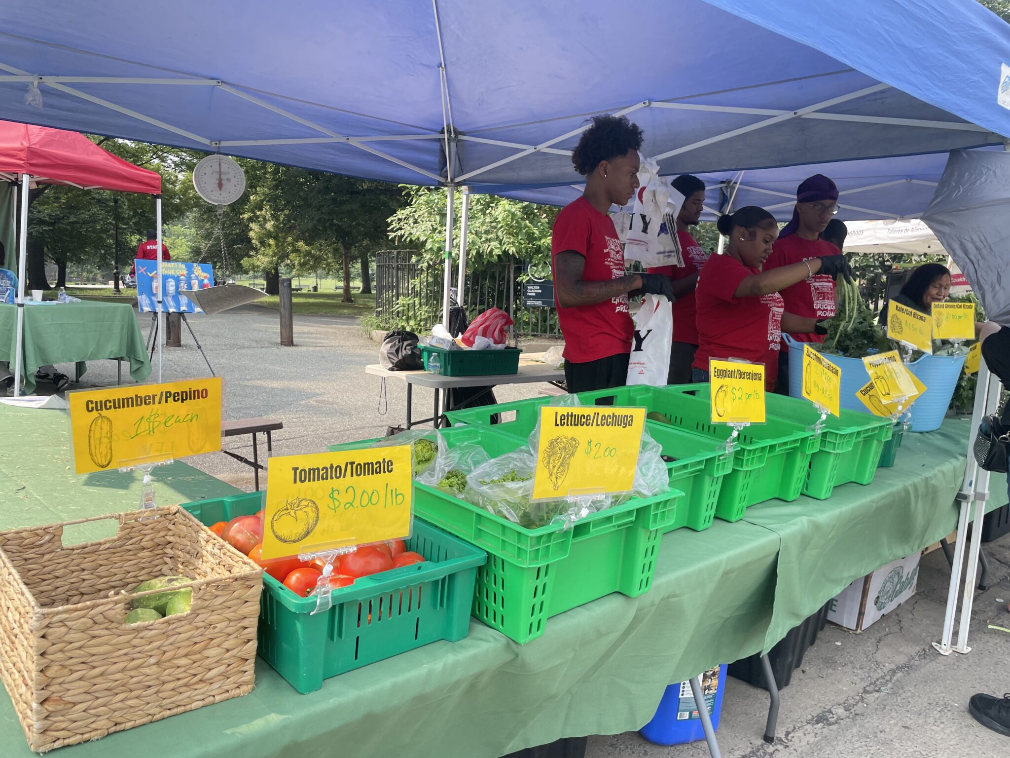A vegetable stand with people standing nearby