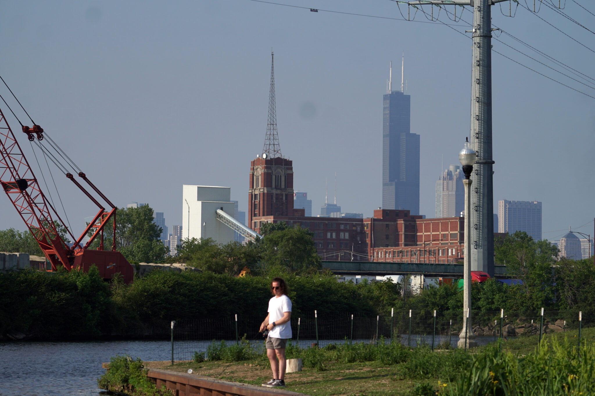 A person standing by the water with a city behind them