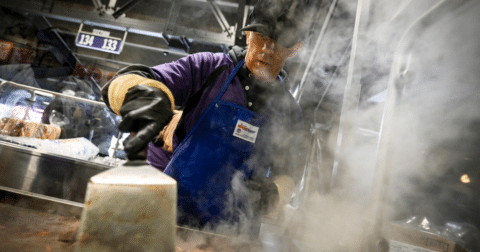 A cook working on a grill that is steaming