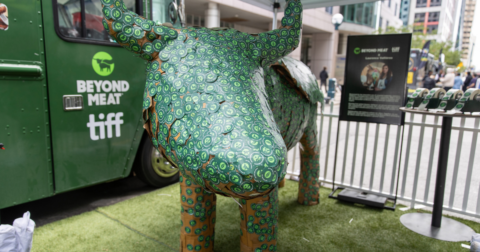 A large cow figure with green stickers all over