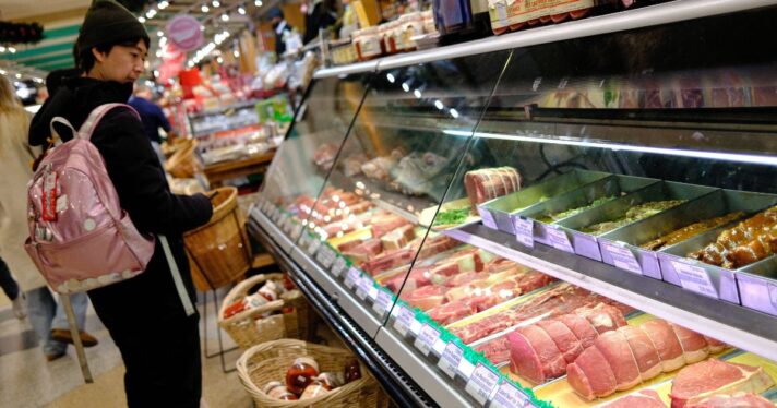 A man shops for meat in a grocery store.