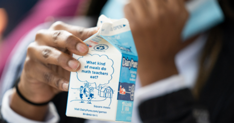 A child's hand holding a milk carton