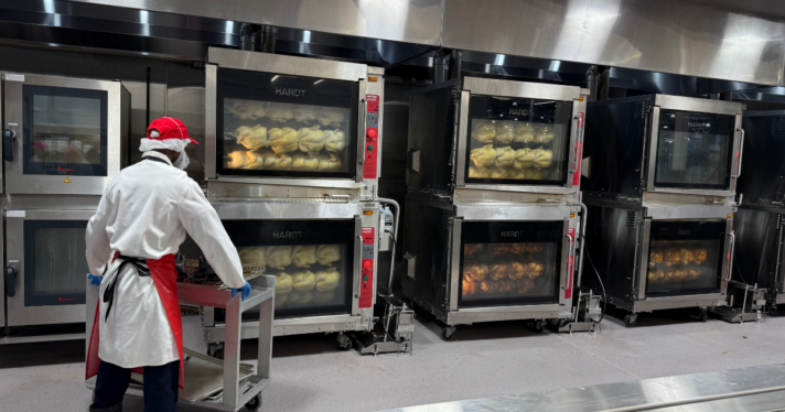 A Costco worker cooking multiple chickens