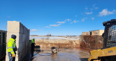 Two men in work uniforms cleaning a messy area