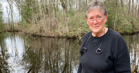 A woman standing in front of a dirty creek