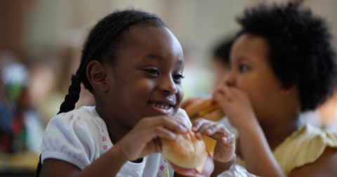 A young girl eating a school lunch