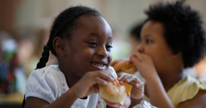 A young girl eating a school lunch