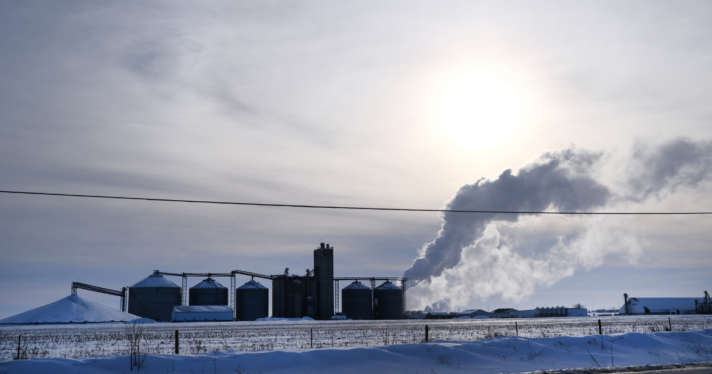 A factory by the roadside with smoke coming out of it