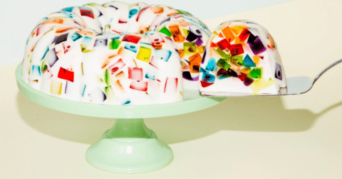 White jello mould with multi-colored insides on top of a pastel green platter