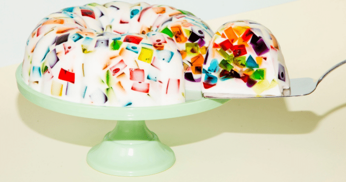White jello mould with multi-colored insides on top of a pastel green platter