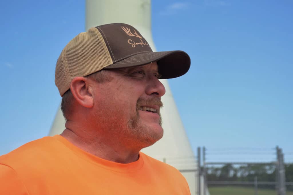 A man with an orange shirt and brown hat