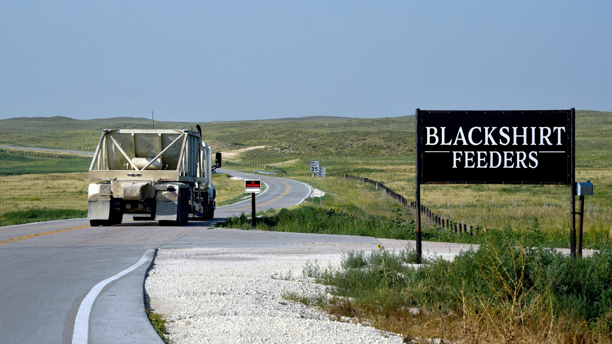 A truck driving by a sign that reads: Blackshirt Feeders