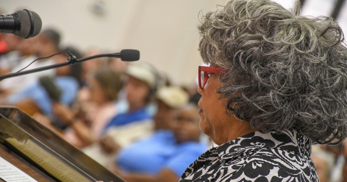 A woman talking in a mic at a townhall