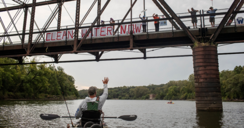 Chris Jones waves to supporters demonstrating for clean water in Des Moines, Iowa. Jones, a retired scientist and water advocate, is running for Iowa’s secretary of agriculture.
