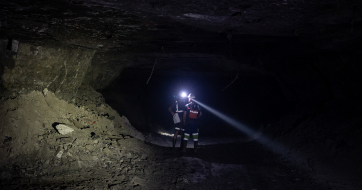 Two miners walking in a dark mine